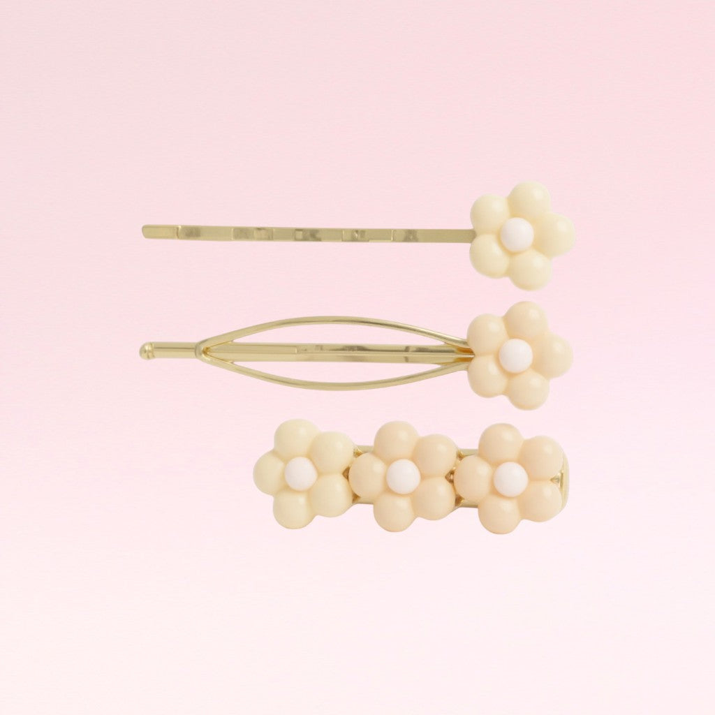 Set of three floral hair pins on a pink background