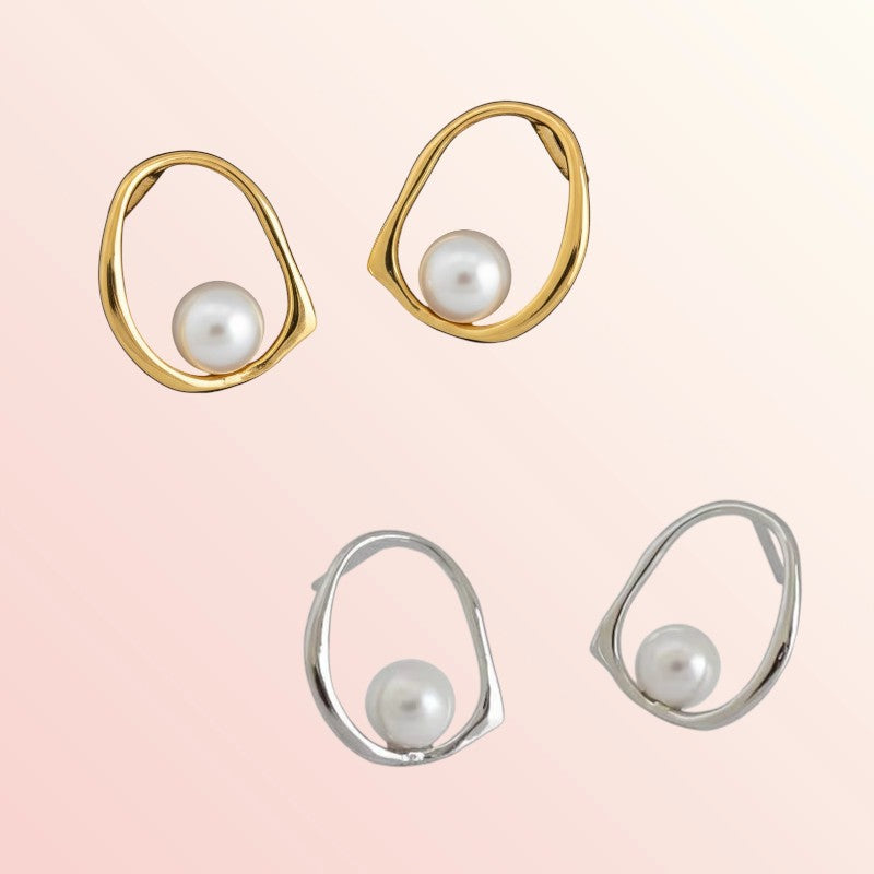 Pair of gold and silver earrings with pearls on a light pink background