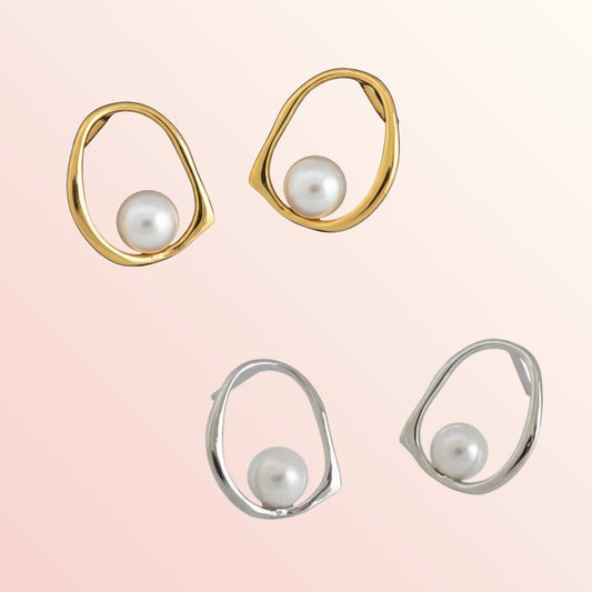 Pair of gold and silver earrings with pearls on a light pink background