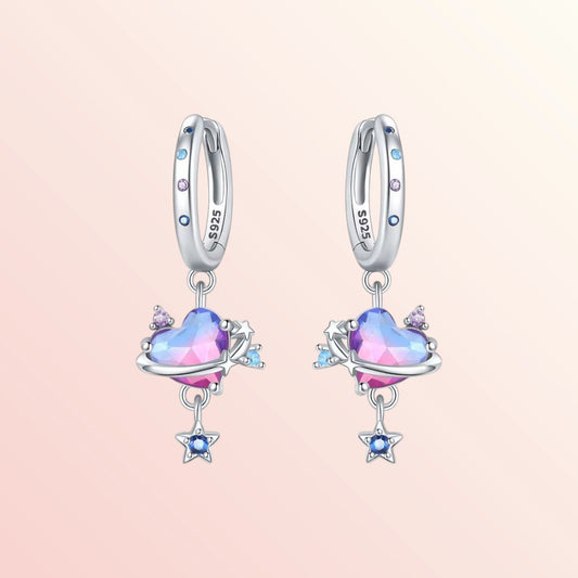 Pair of silver earrings with heart-shaped gemstones on a pink background