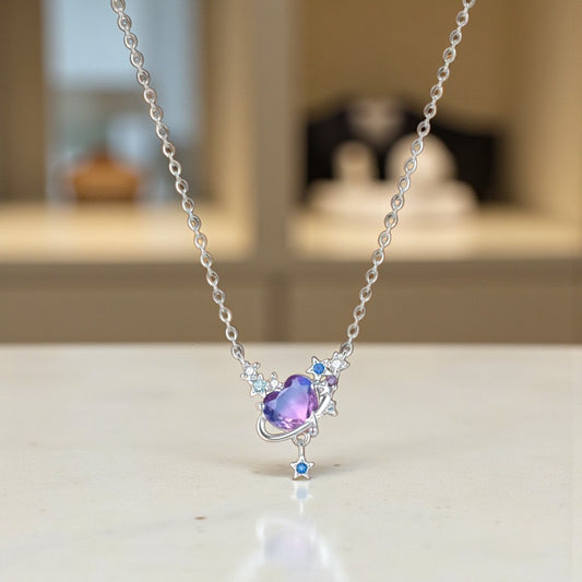 Silver necklace with a heart-shaped purple gemstone on a light surface.
