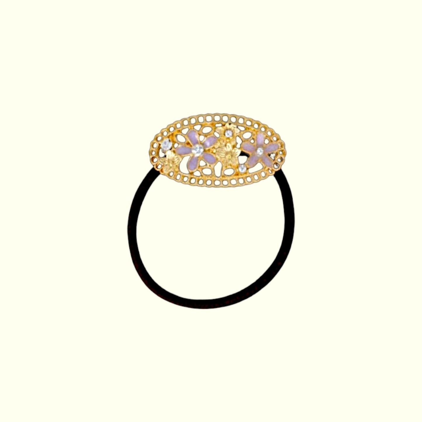 Decorative hair tie with a gold ring and floral design on a white background
