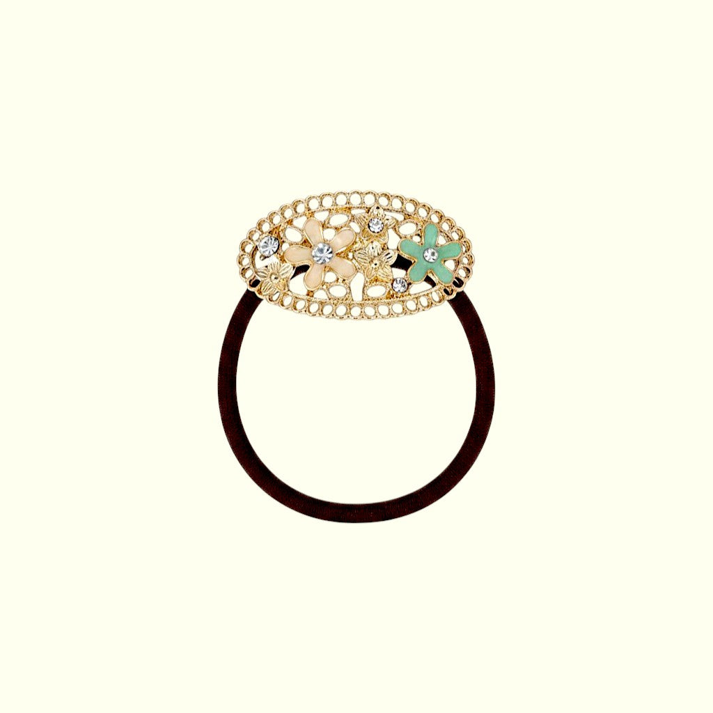 Decorative hair tie with gold clasp and green flower on a white background