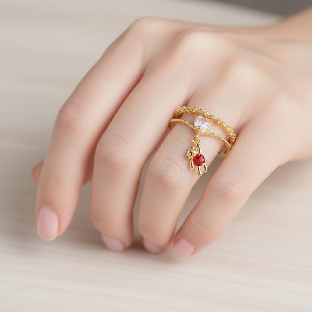 Close-up of a hand wearing a gold ring with a red gemstone on a neutral background