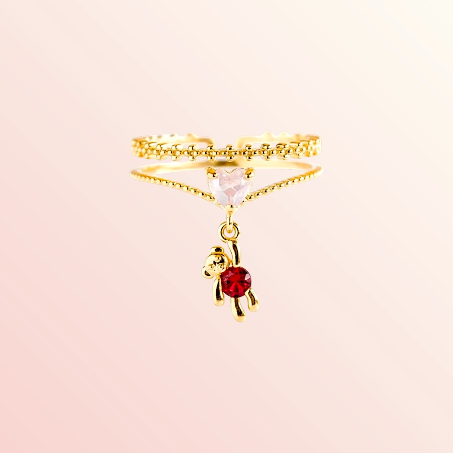 Gold ring with a small red gemstone on a beige background