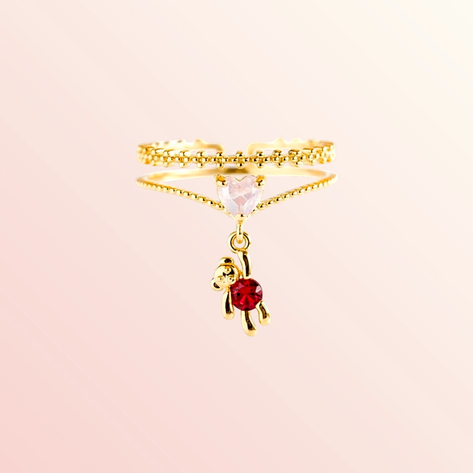 Gold ring with a small red gemstone on a beige background