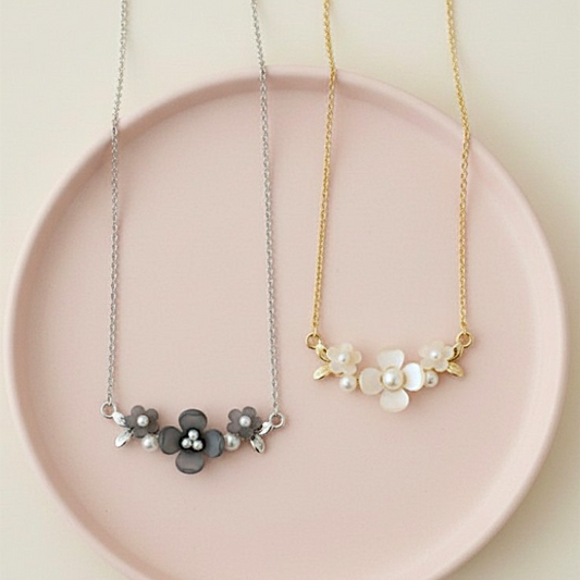 Two floral necklaces on a pink plate with a light background