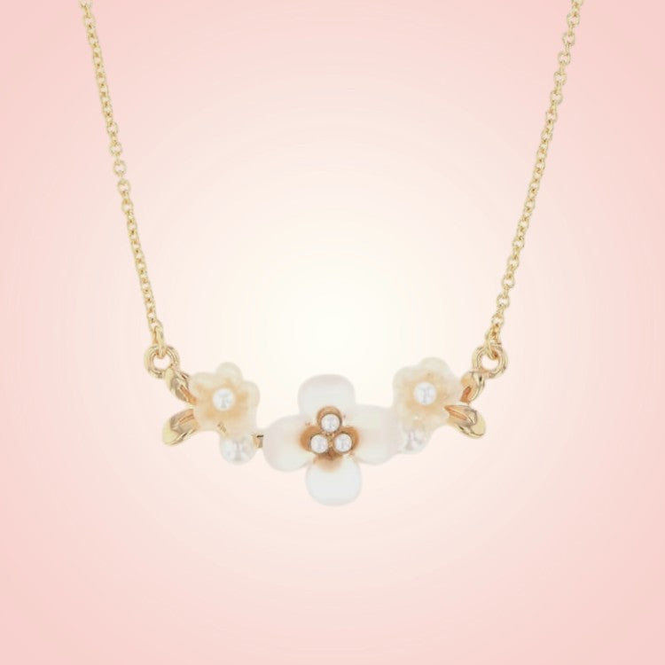 Necklace with floral pendants on a soft pink background