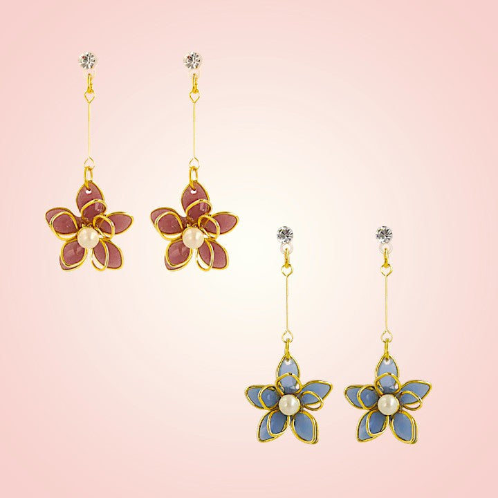 Floral earrings with gold and blue accents on a pink background
