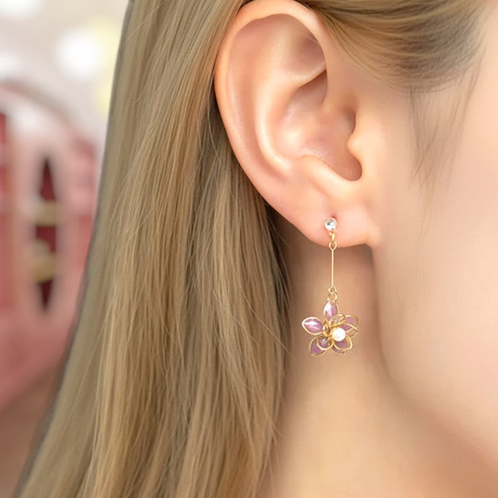 Close-up of an ear wearing a floral earring with pink and purple stones.