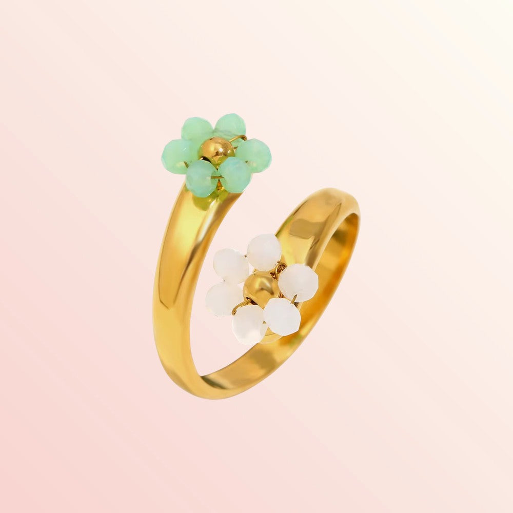 Gold ring with green and white floral designs on a pink background