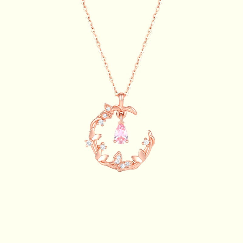 Rose gold necklace with a pink gemstone pendant on a light pink background