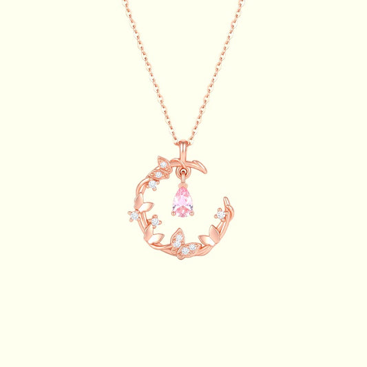 Rose gold necklace with a pink gemstone pendant on a light pink background