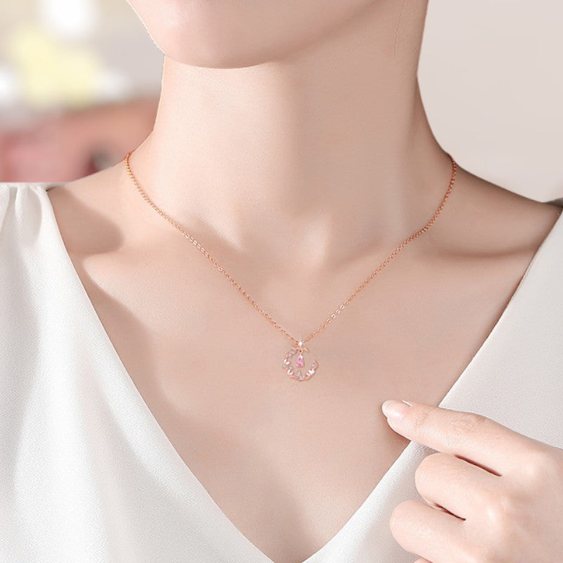 Necklace with a pink pendant worn by a person in a white top