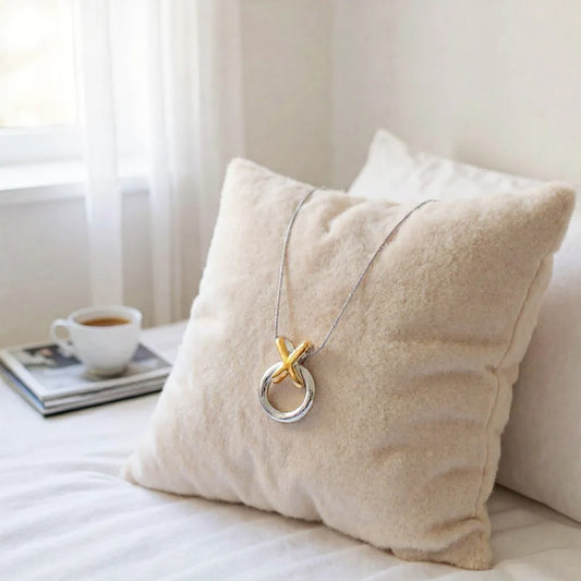 Necklace with a unique design draped over a beige pillow on a bed.