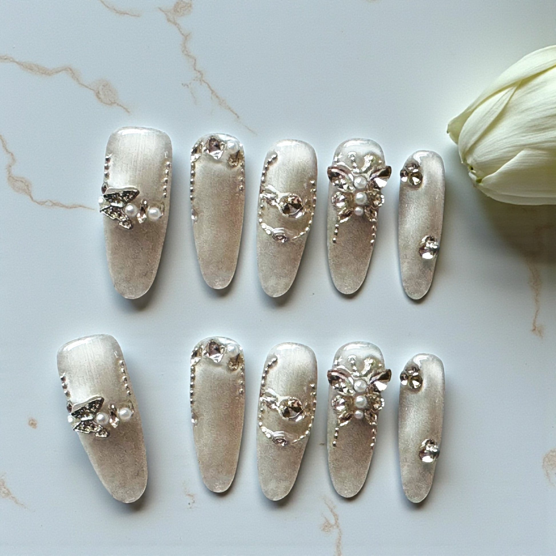 Decorative silver nail art designs on a marble surface with a white flower.