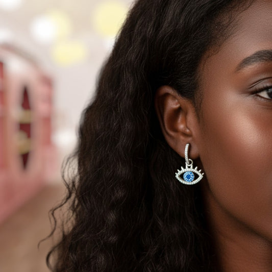 Close-up of a woman wearing an eye-shaped earring with a blue gemstone.
