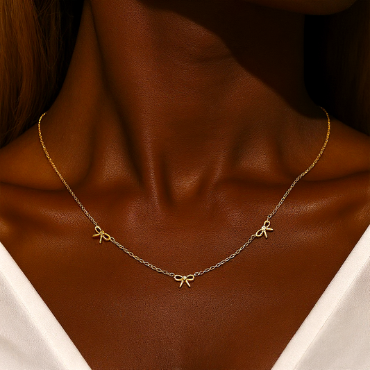 Gold necklace with bow pendants on a brown background