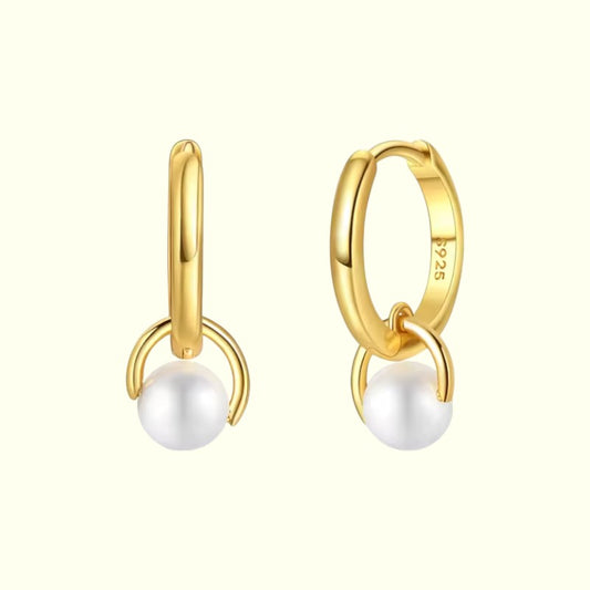 Gold hoop earrings with white pearls on a white background