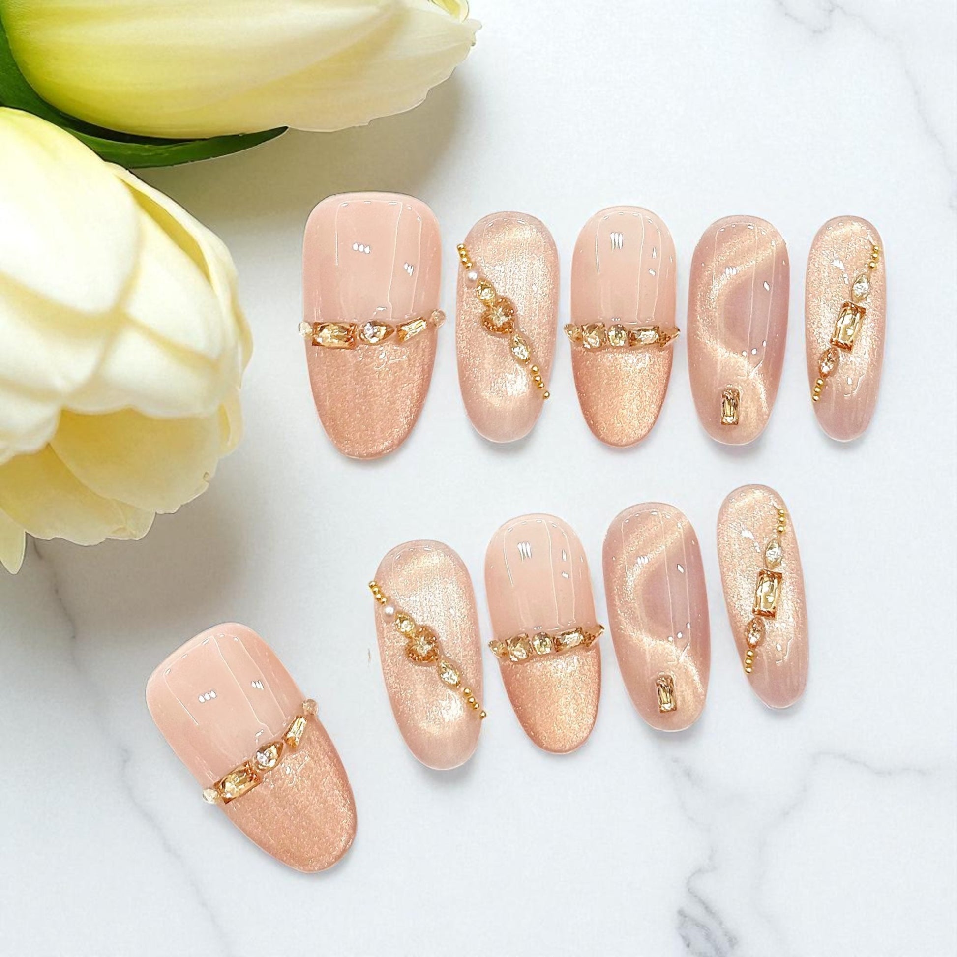 Nail art with gold accents on a white surface with yellow flowers.