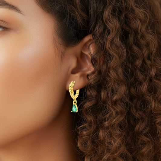 Close-up of a woman wearing a gold earring with a green gemstone.