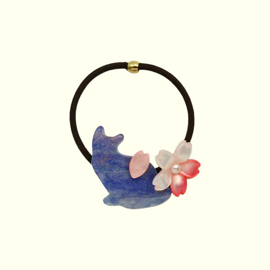 Hair tie with blue cat-shaped charm and pink flower on a white background