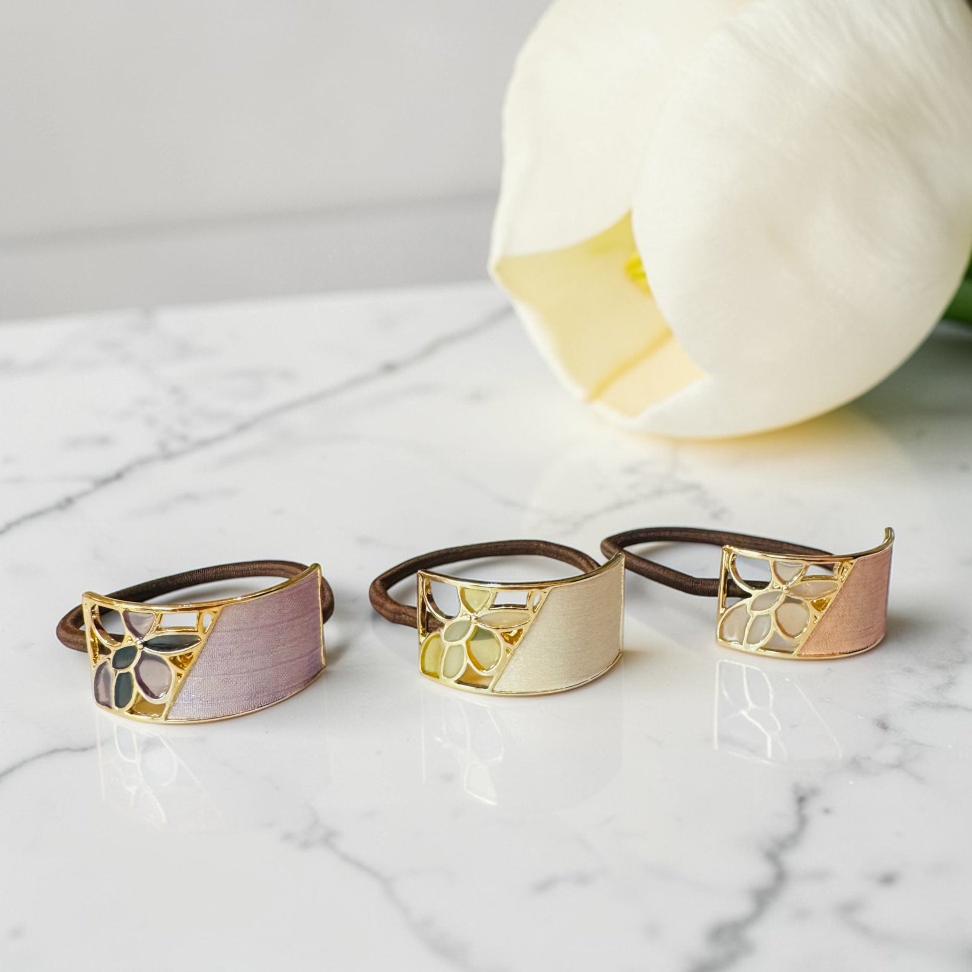 Three decorative rings with gold and brown accents on a marble surface.