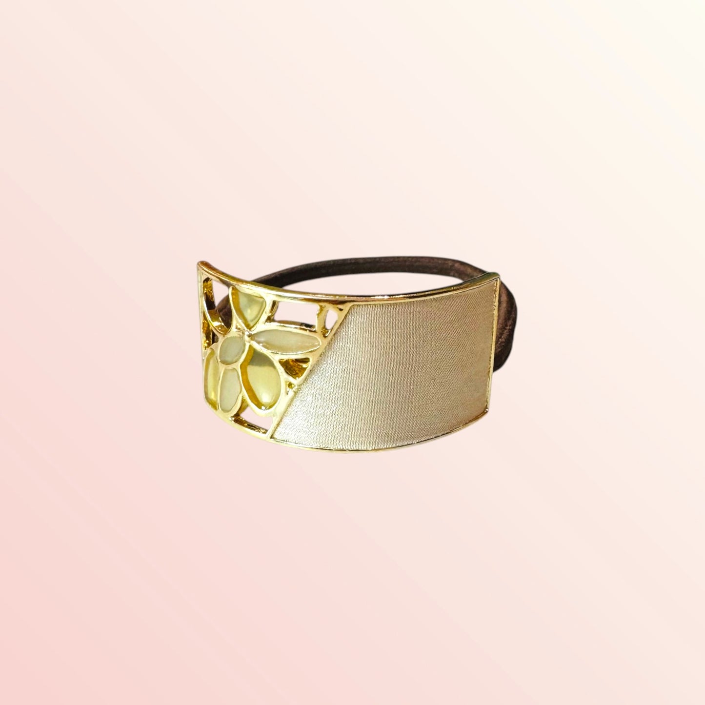 Gold and black hairband on a light pink background