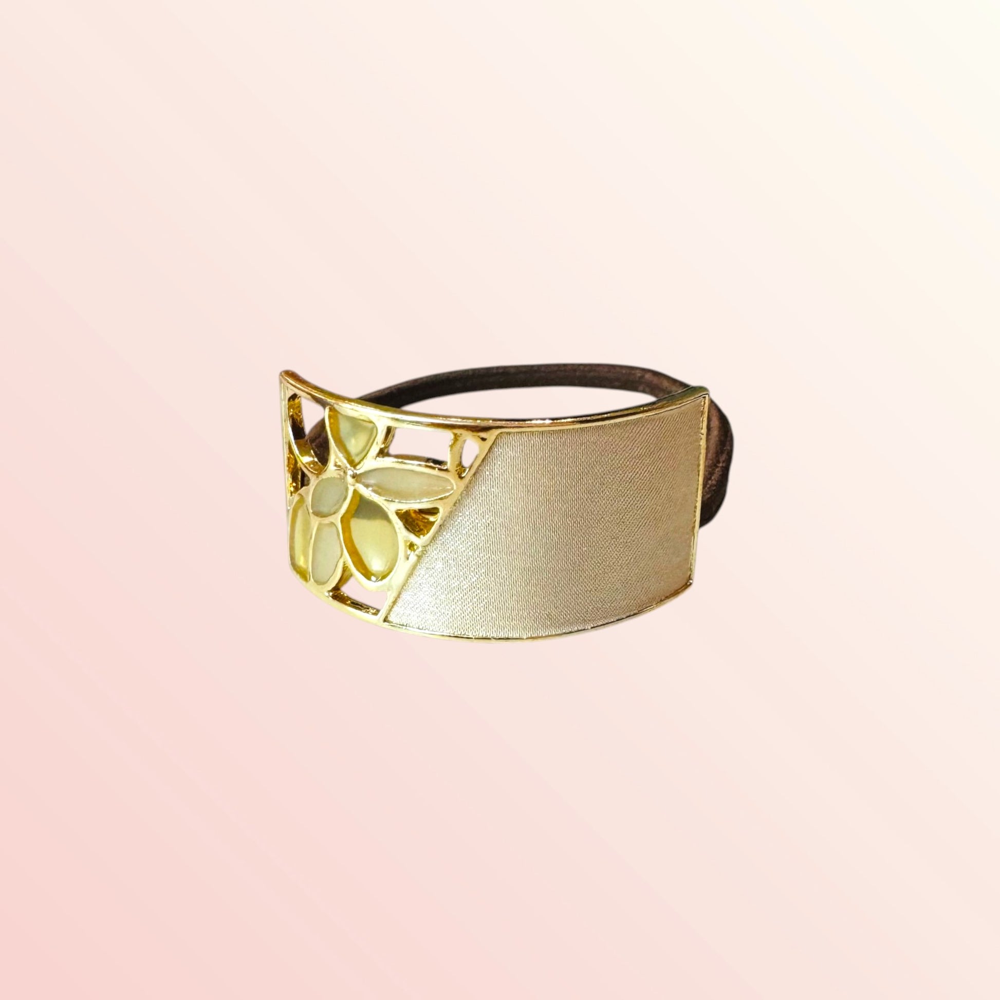 Gold and black hairband on a light pink background