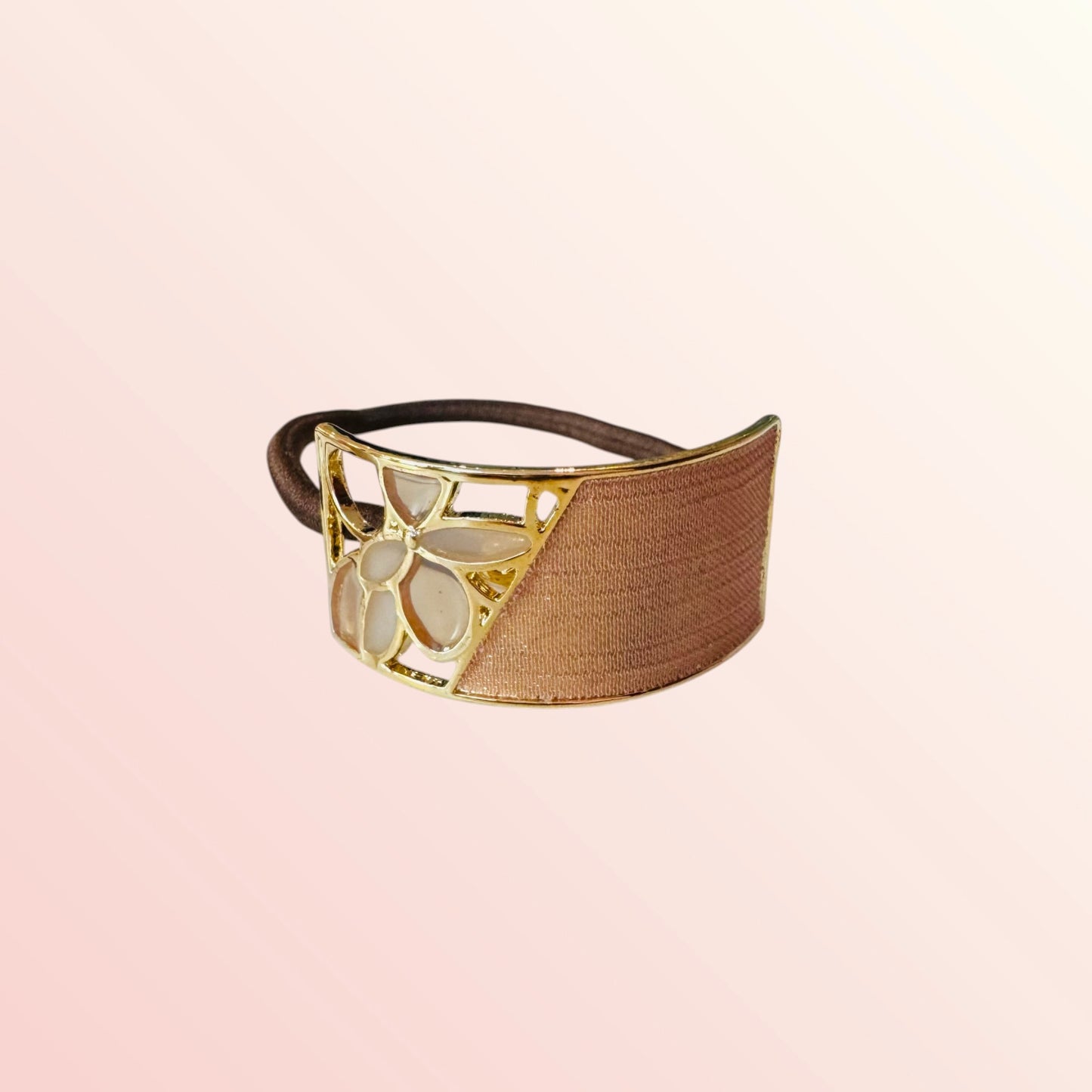 Decorative headband with gold and brown design on a light pink background