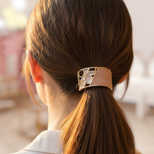 Close-up of a hair tie with decorative design in a person's hair, blurred background