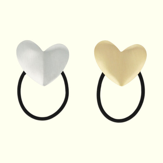 Two heart-shaped hair ties, one white and one gold, on a white background.