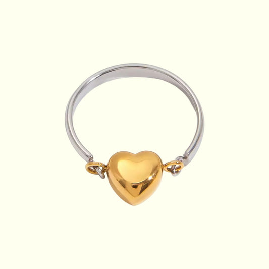 Two-tone ring with a gold heart-shaped charm on a white background