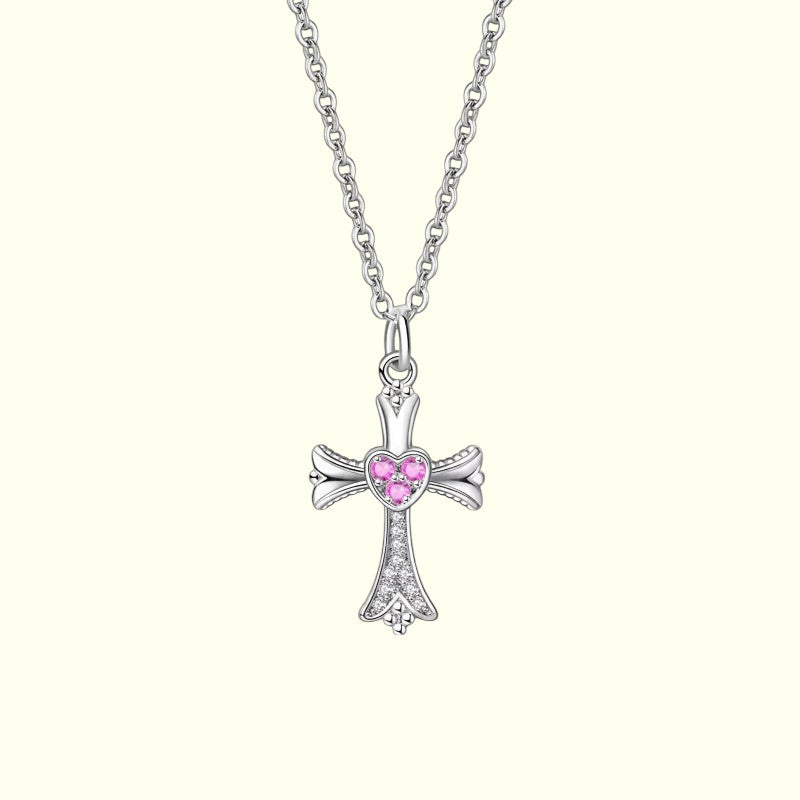 Silver cross necklace with a pink heart-shaped gem on a white background