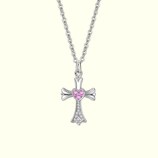 Silver cross necklace with a pink heart-shaped gem on a white background