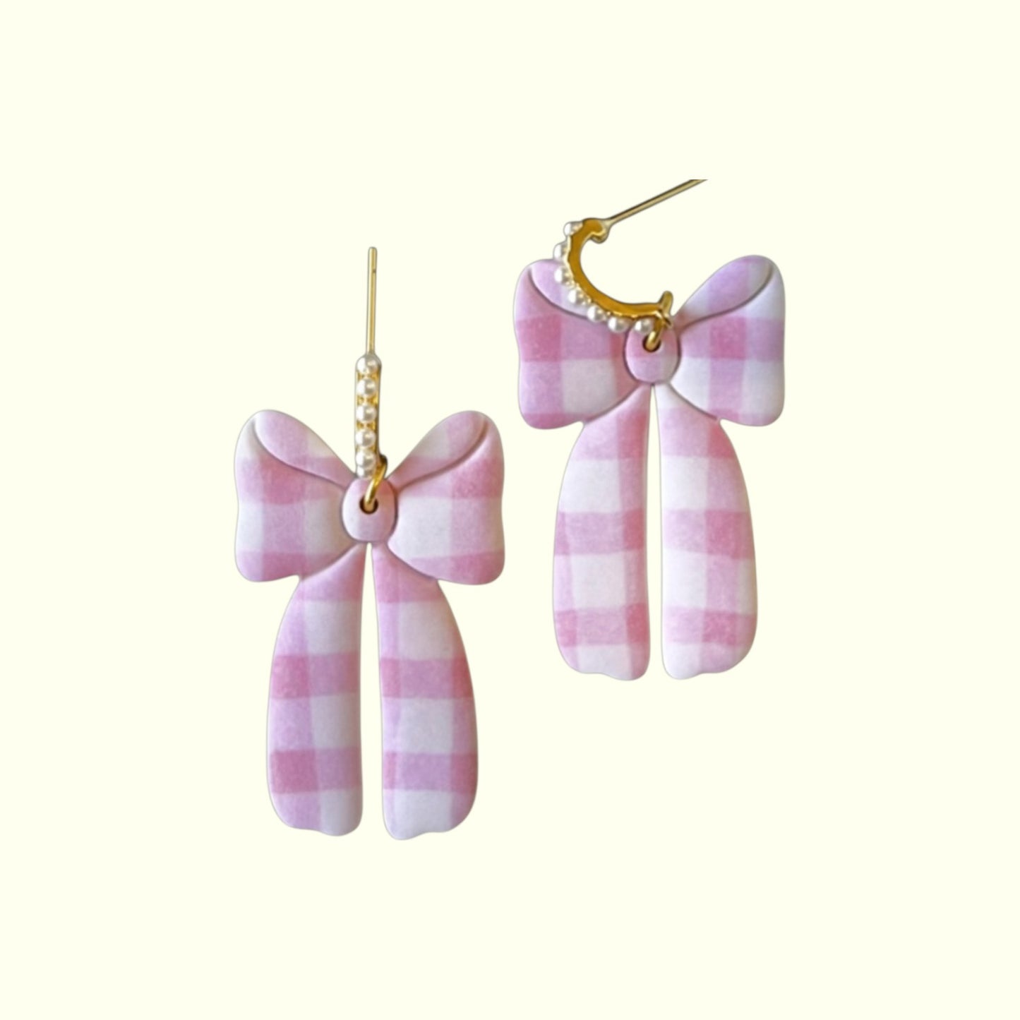 Pink and white checkered bow earrings on a white background