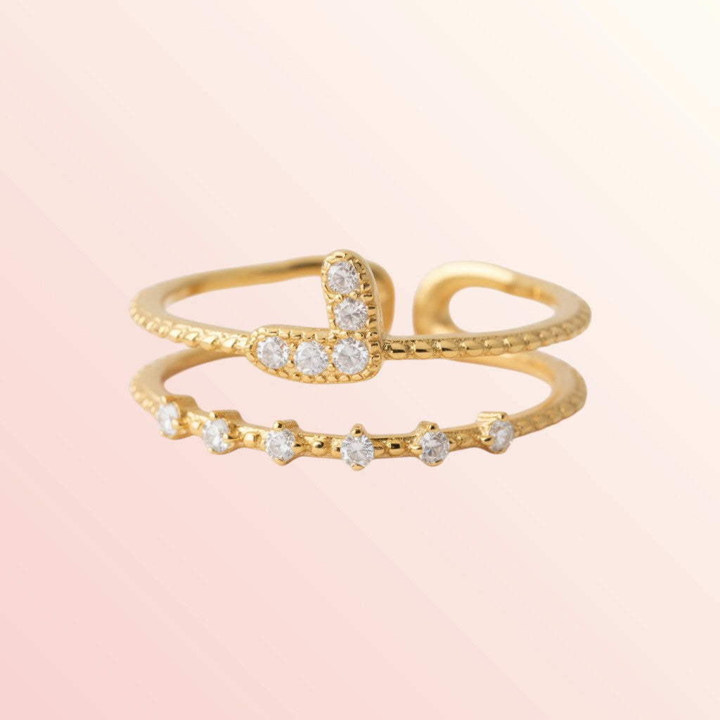 Gold ring with embedded diamonds on a light pink background