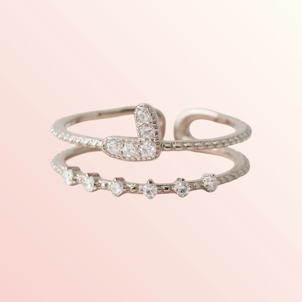 Two silver rings with diamond accents on a light pink background