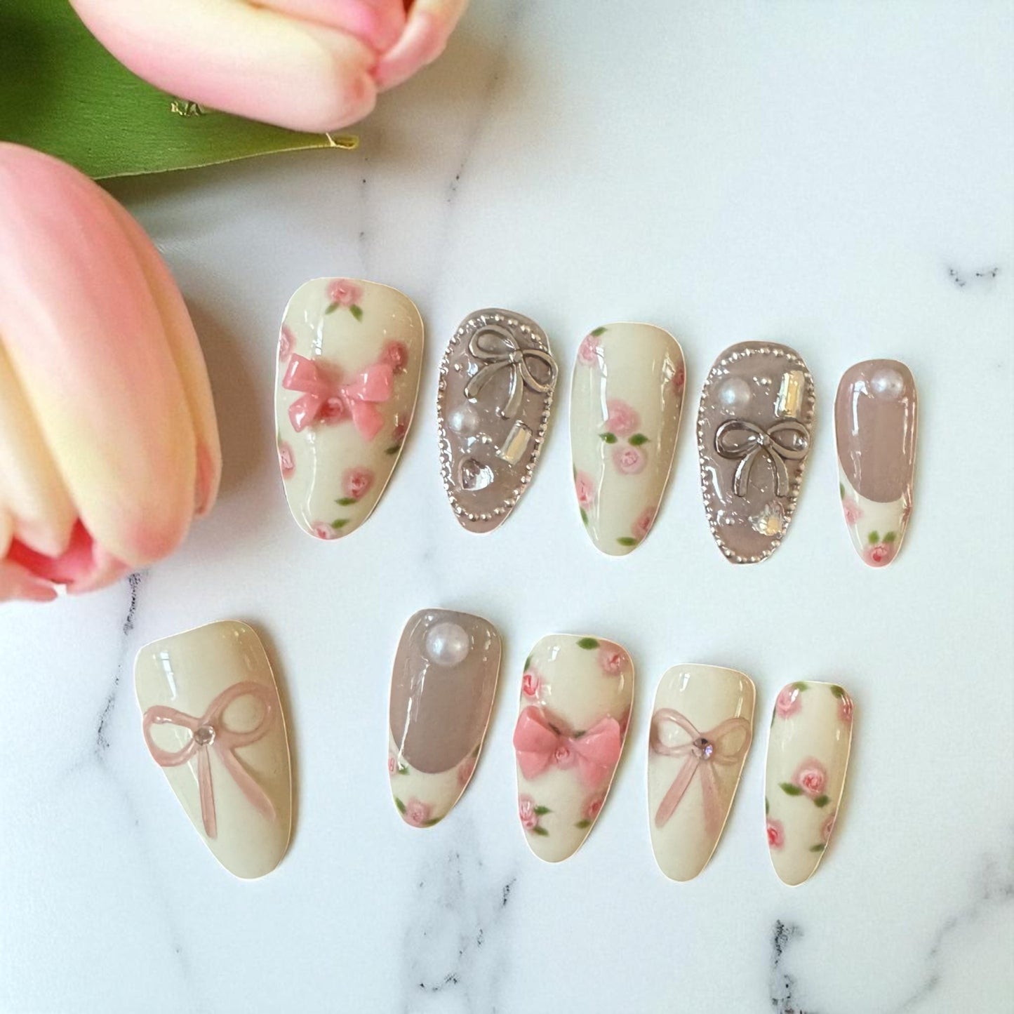Set of decorative nail art designs on a marble surface with tulips.