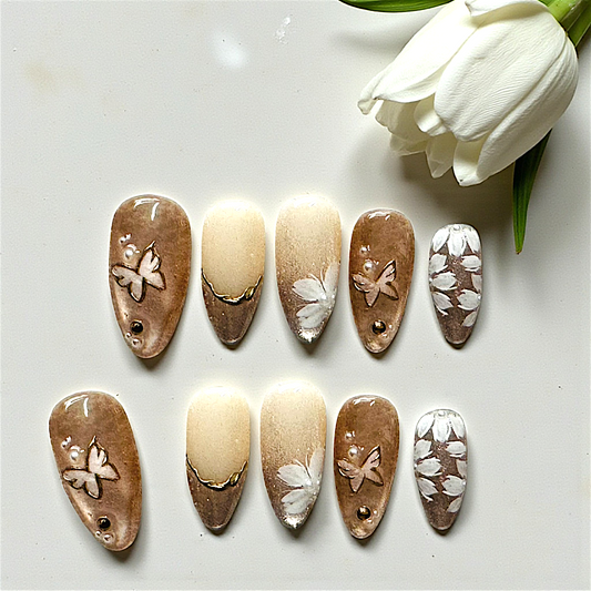 Decorative nail art designs on nails with a white tulip in the background