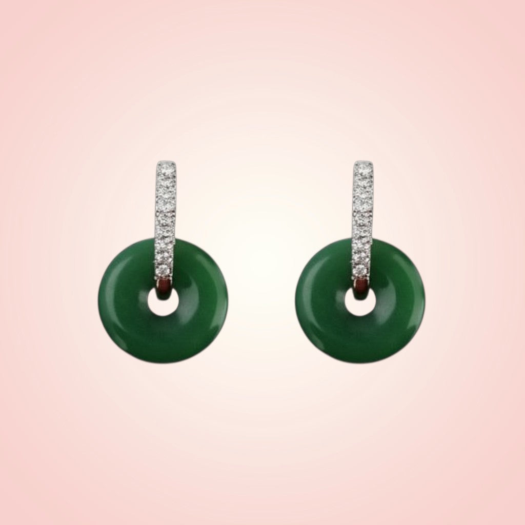 Pair of green earrings with diamond-studded hoop on a pink background