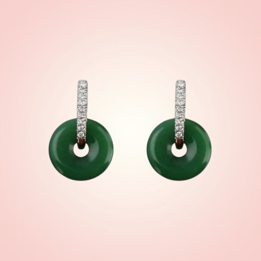 Pair of green earrings with diamond-studded hoop on a pink background