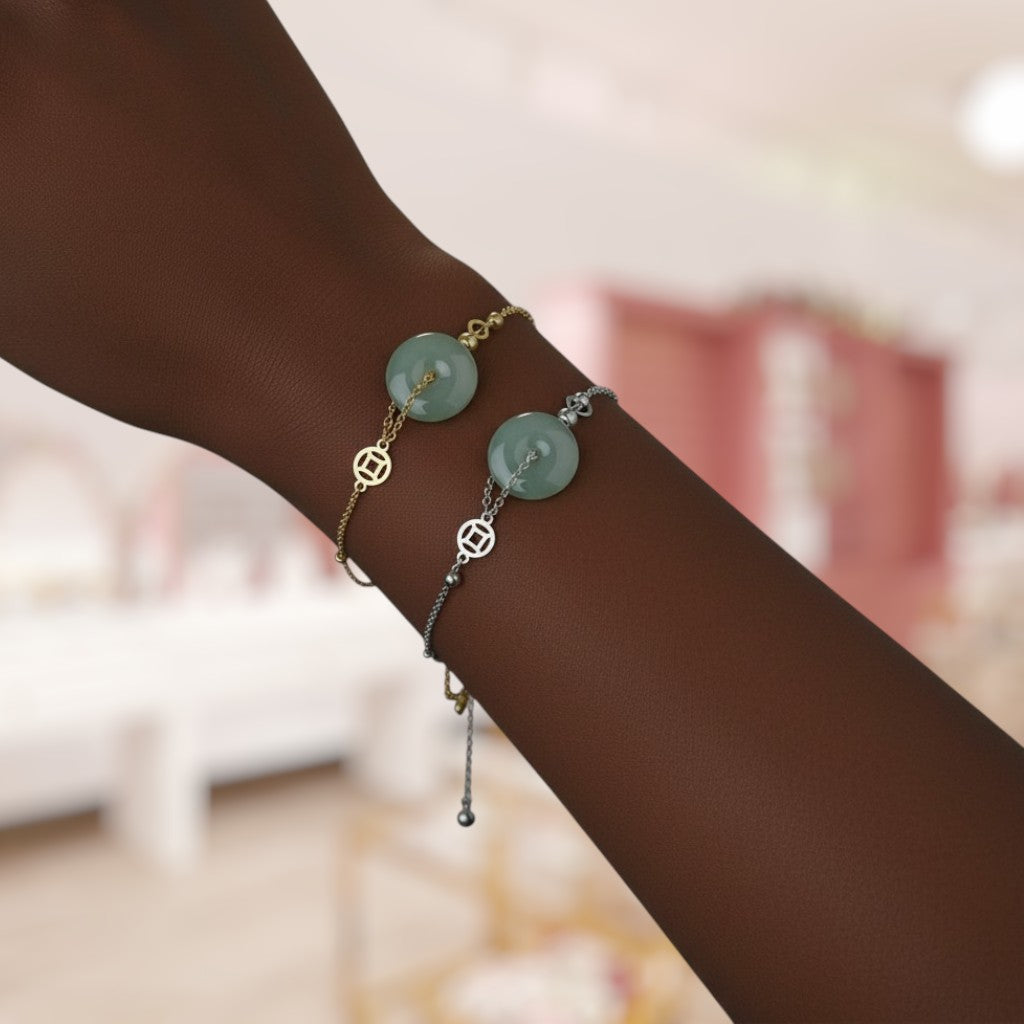 Bracelets with green stones and gold accents on a wrist against a blurred indoor background