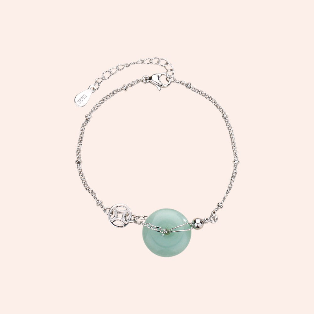 Silver bracelet with a turquoise bead on a light pink background