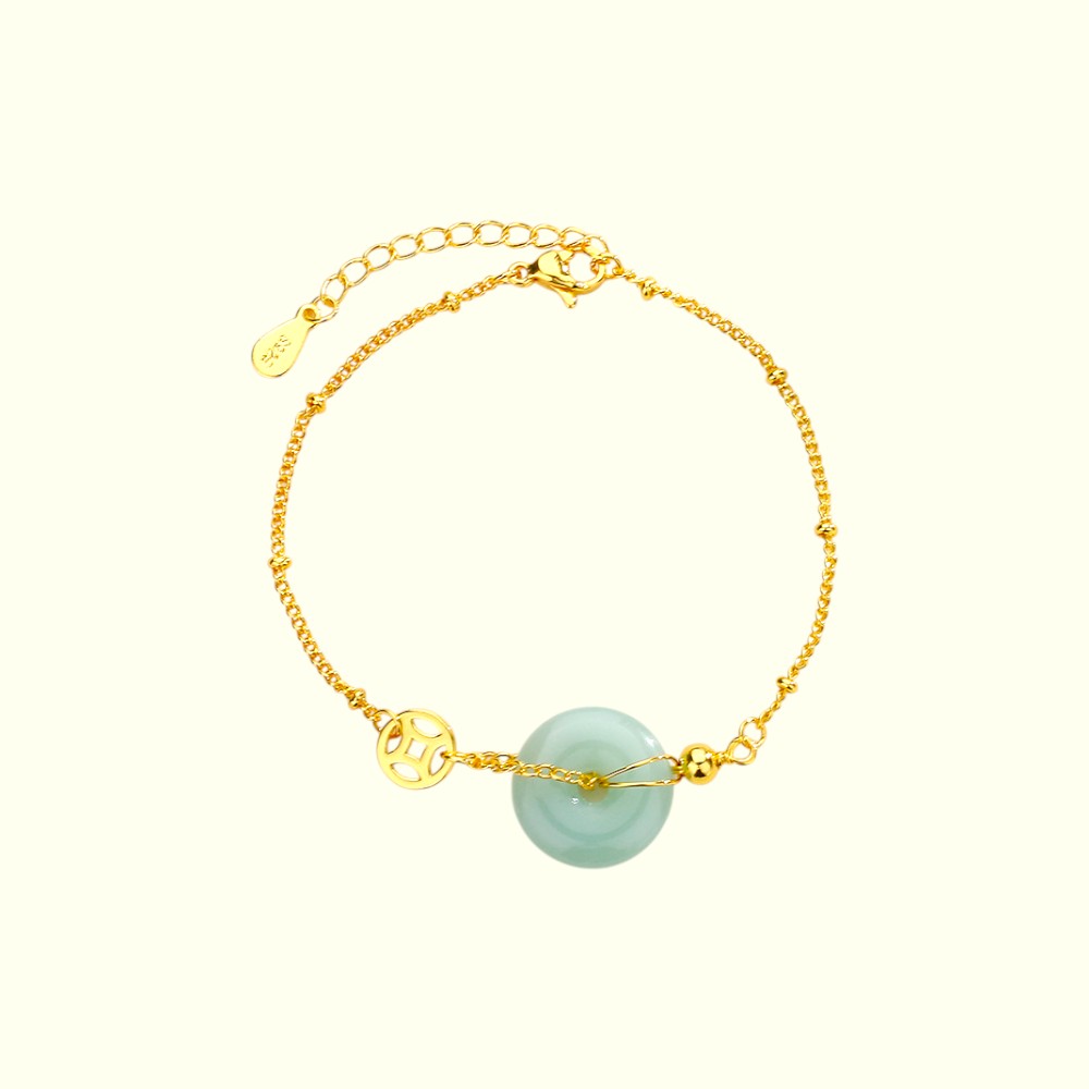 Gold bracelet with a green gemstone on a white background