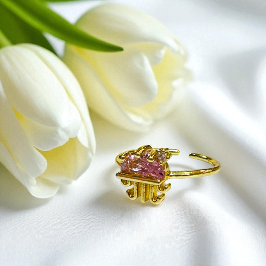 Gold Jellyfish ring with pink gemstone next to white tulips on a white background