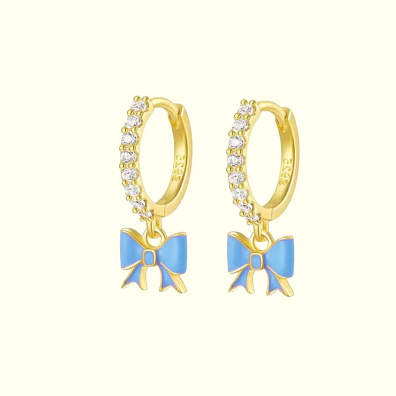 Gold hoop earrings with blue bow charms on a white background