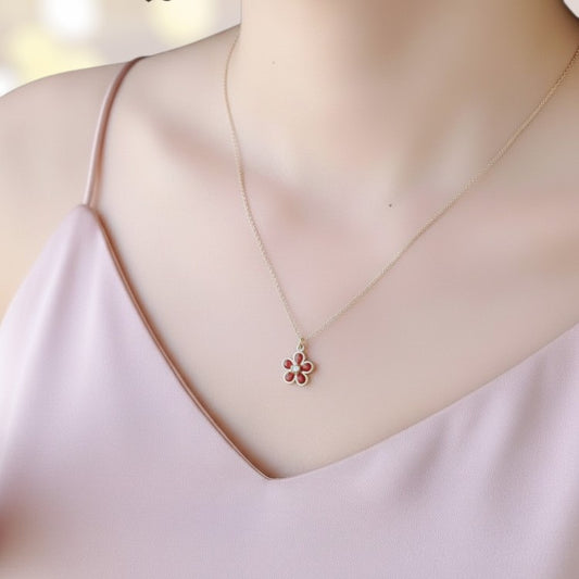 Necklace with a floral pendant on a mannequin wearing a light pink top.