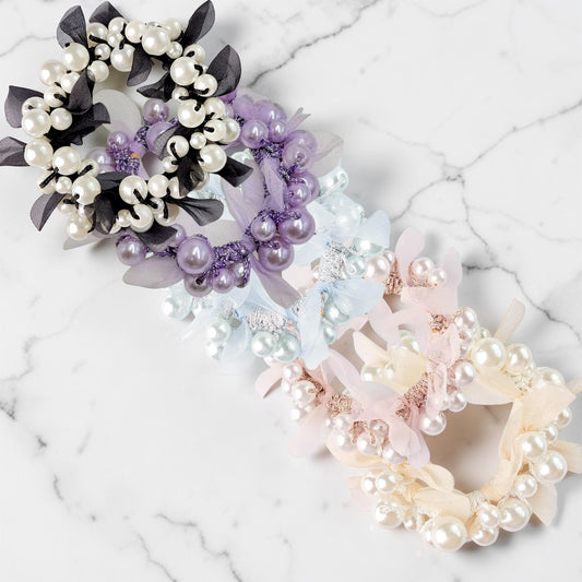 Three pearl hair ties in different colors on a marble surface