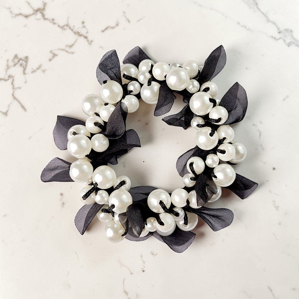 Decorative wreath with pearls and black ribbons on a marble surface